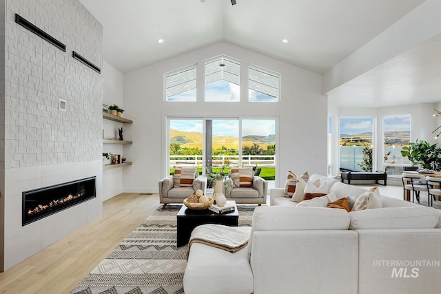 living area featuring a tile fireplace, a healthy amount of sunlight, recessed lighting, and light wood finished floors
