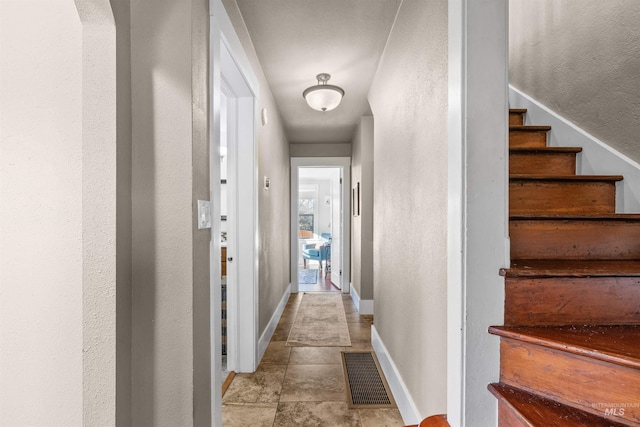 hall featuring stairs, visible vents, and baseboards