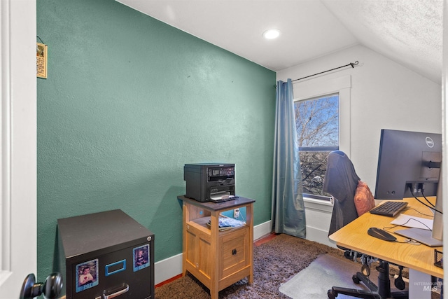 office area featuring lofted ceiling, a textured wall, and baseboards