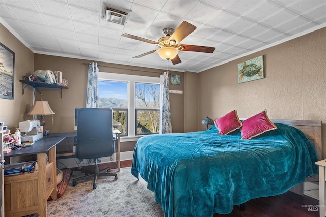 bedroom with ornamental molding, a textured wall, and wood finished floors