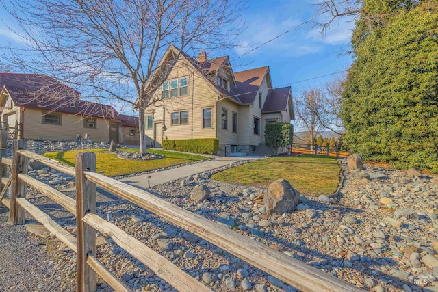 view of property exterior featuring a yard, fence, and a chimney