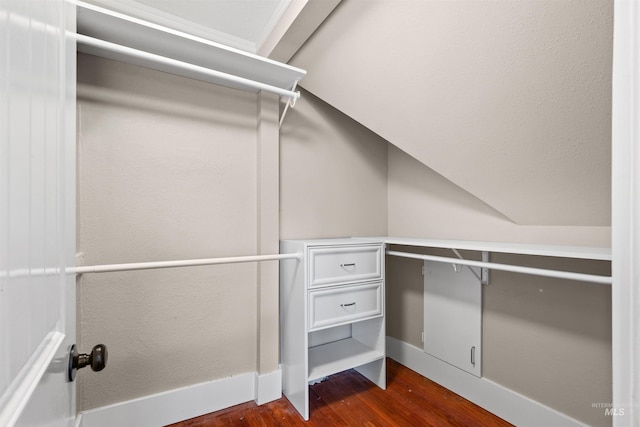 spacious closet with dark wood-style flooring and vaulted ceiling