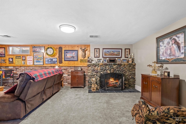 living room featuring a textured ceiling, a stone fireplace, carpet flooring, and visible vents