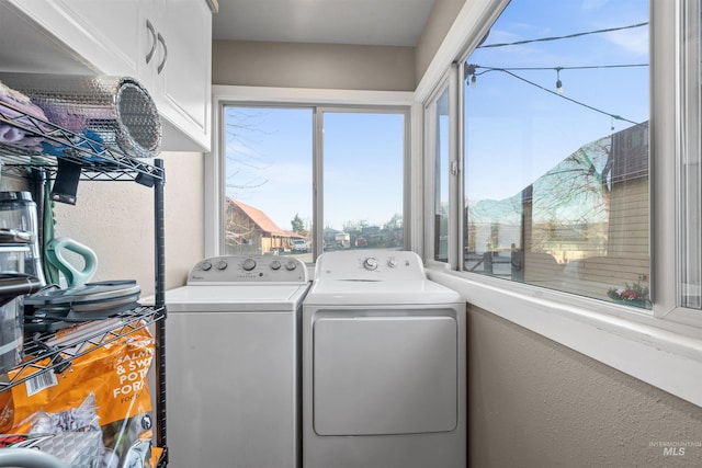 clothes washing area with cabinet space and washing machine and dryer