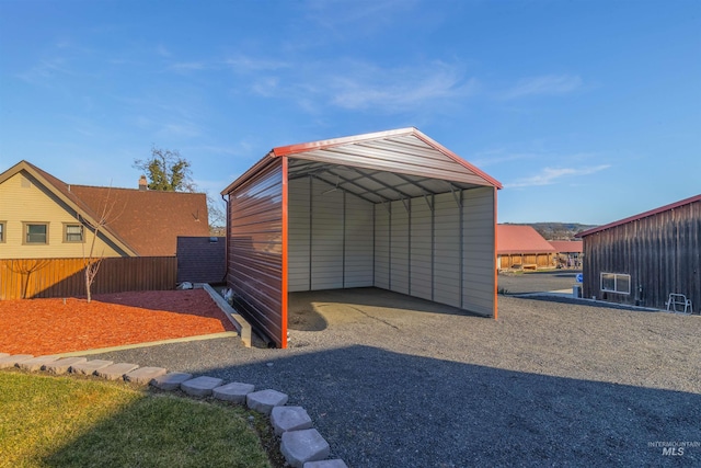 view of outbuilding with a carport, fence, and driveway