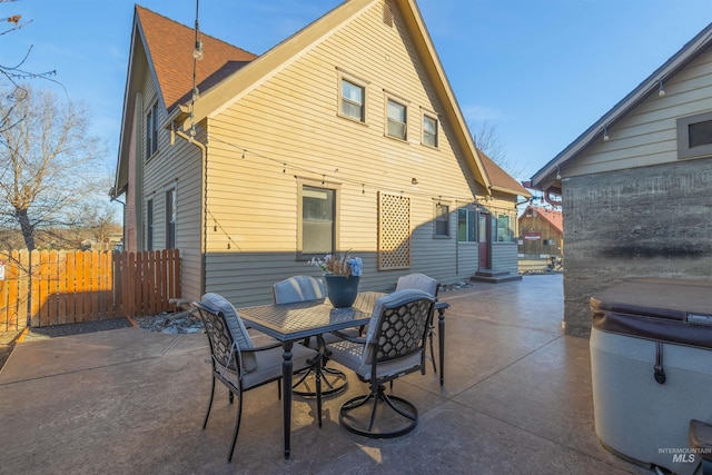 rear view of house with outdoor dining area, a patio area, and fence