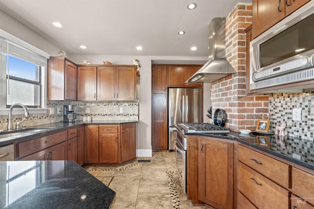 kitchen featuring wall chimney exhaust hood, brown cabinetry, a sink, and stainless steel appliances