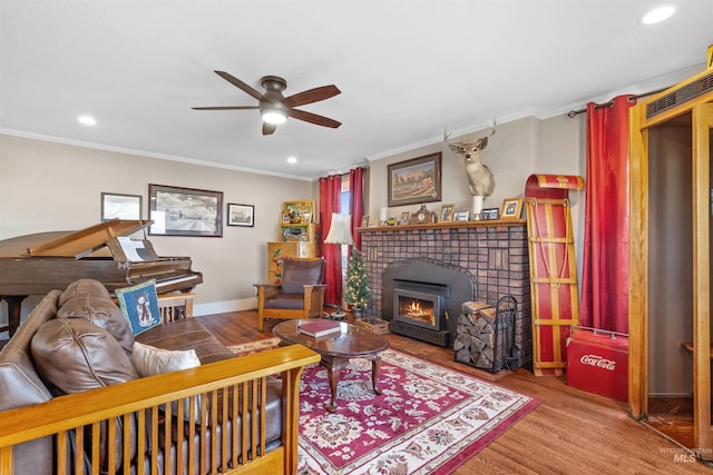 living area featuring ornamental molding, a brick fireplace, ceiling fan, wood finished floors, and baseboards