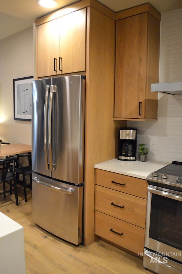 780 Village Dr Unit 308, Donnelly, ID 83615 - kitchen featuring wall chimney range hood, light countertops, appliances with stainless steel finishes, and light wood-style floors