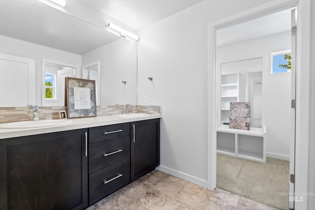 full bath featuring tasteful backsplash, double vanity, and baseboards
