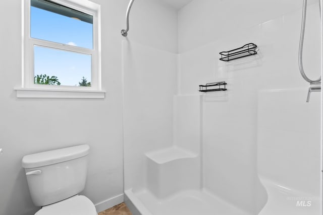 bathroom featuring a shower, toilet, and baseboards