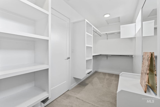 walk in closet with light carpet and attic access