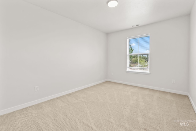 empty room featuring baseboards and light colored carpet