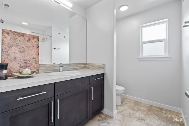bathroom featuring baseboards, backsplash, toilet, vanity, and a shower