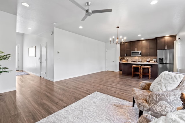 living area with a chandelier, wood finished floors, ceiling fan, recessed lighting, and baseboards
