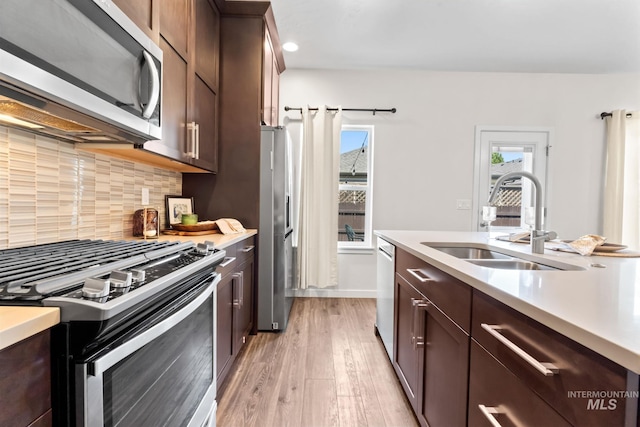 kitchen with stainless steel appliances, a sink, light countertops, light wood-style flooring, and recessed lighting