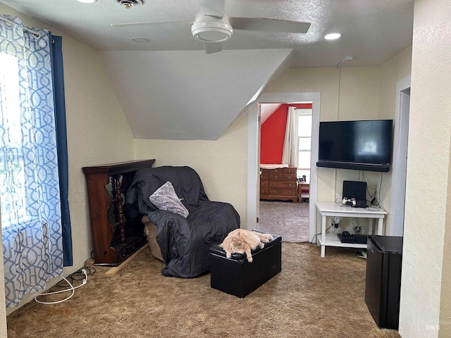 interior space featuring ceiling fan, carpet floors, a textured ceiling, and lofted ceiling