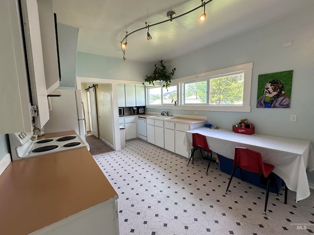 kitchen with white dishwasher, white cabinetry, stove, sink, and track lighting