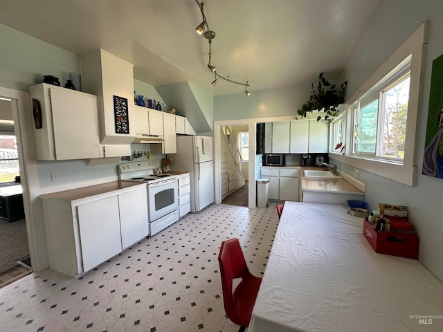 kitchen with white appliances, light carpet, rail lighting, sink, and white cabinetry