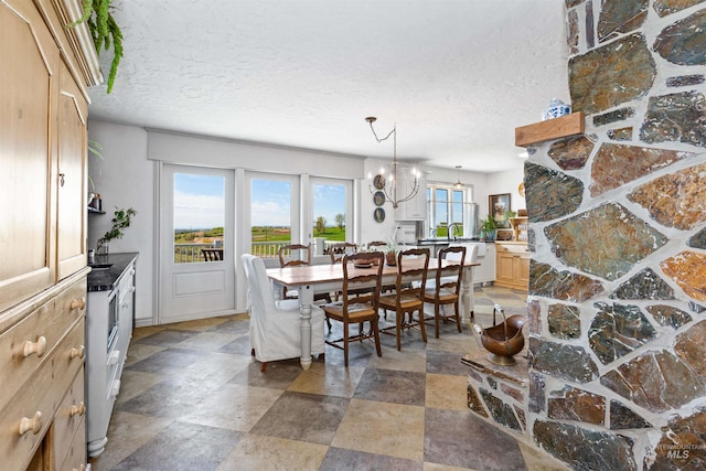 dining area with stone finish floor, a textured ceiling, and a chandelier