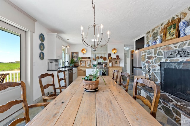 dining space featuring an inviting chandelier, a textured ceiling, and a stone fireplace