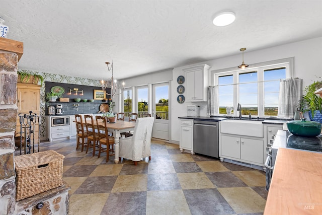 kitchen with hanging light fixtures, appliances with stainless steel finishes, a sink, an inviting chandelier, and a textured ceiling