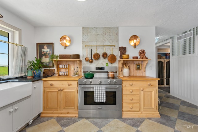 kitchen with electric range, a textured ceiling, wooden counters, and a sink