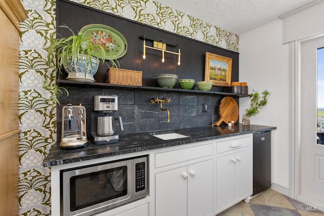 bar featuring stainless steel microwave, decorative backsplash, and a sink