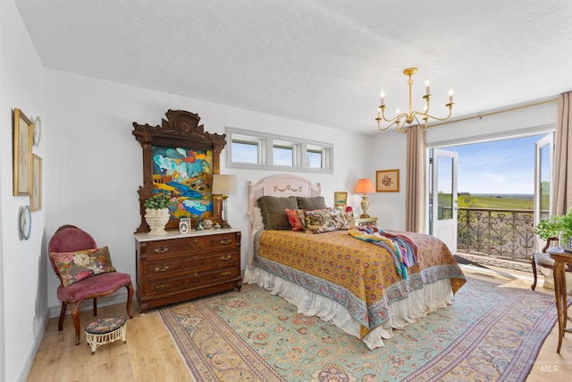 bedroom featuring access to outside, a notable chandelier, multiple windows, and light wood-type flooring
