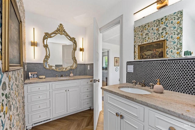 bathroom featuring wallpapered walls, two vanities, and a sink