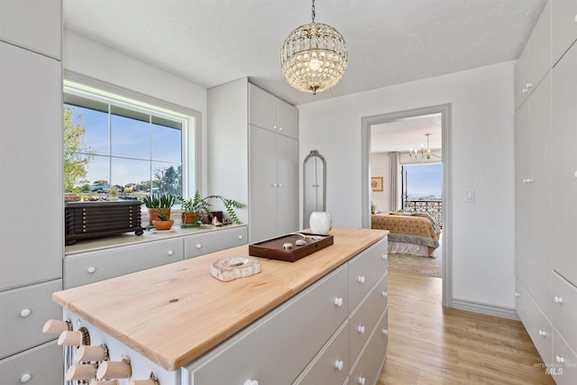 interior space featuring white cabinetry, a notable chandelier, light wood finished floors, and a center island