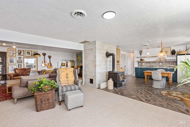 living room with visible vents, a wood stove, and a textured ceiling