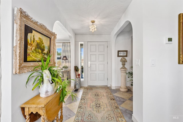 entrance foyer with arched walkways and baseboards