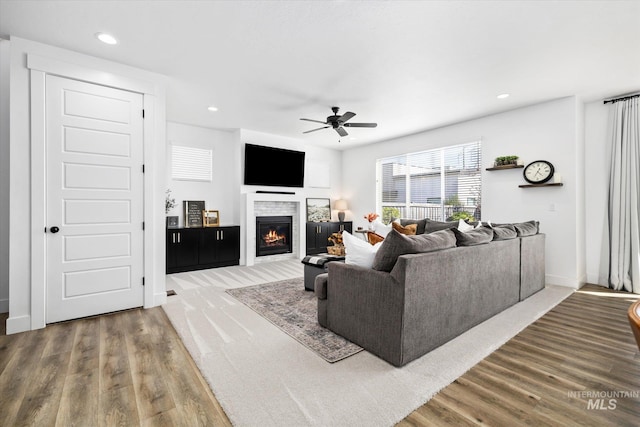 living room with a glass covered fireplace, recessed lighting, wood finished floors, and a ceiling fan