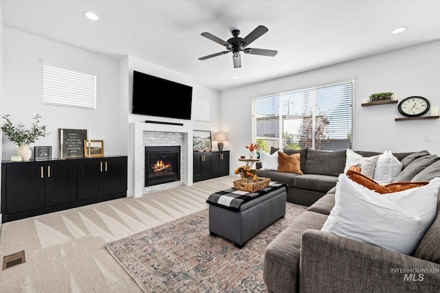 carpeted living room with visible vents, recessed lighting, a ceiling fan, and a glass covered fireplace