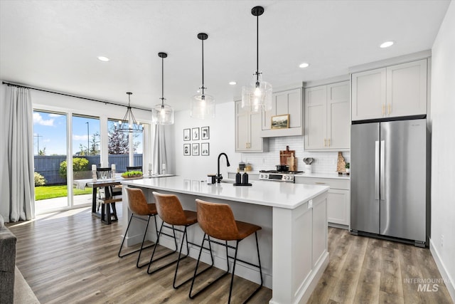 kitchen featuring light countertops, decorative backsplash, freestanding refrigerator, stove, and a sink