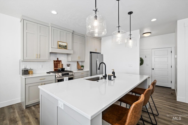 kitchen featuring tasteful backsplash, a center island with sink, appliances with stainless steel finishes, and dark wood-style flooring