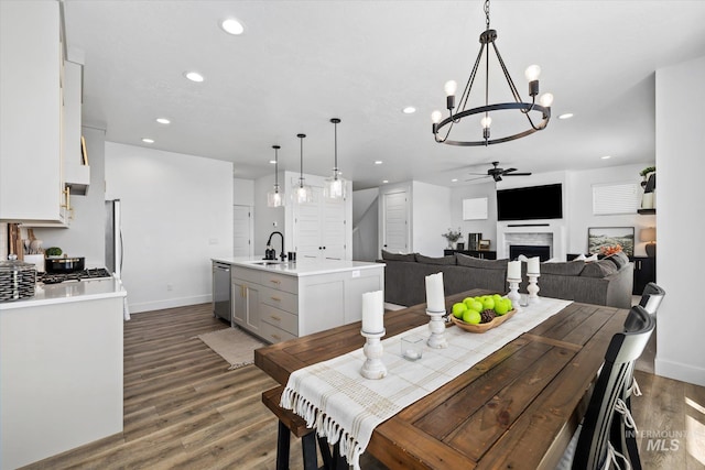 dining space featuring a ceiling fan, wood finished floors, recessed lighting, and a fireplace