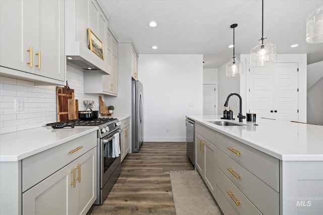 kitchen featuring dark wood finished floors, a sink, light countertops, appliances with stainless steel finishes, and backsplash