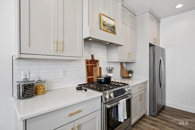 kitchen with baseboards, stainless steel appliances, dark wood-type flooring, light countertops, and backsplash