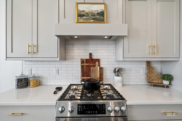 kitchen with tasteful backsplash, stainless steel range with gas stovetop, light countertops, and exhaust hood