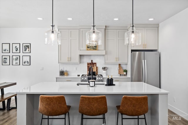 kitchen featuring tasteful backsplash, a breakfast bar area, light countertops, and freestanding refrigerator