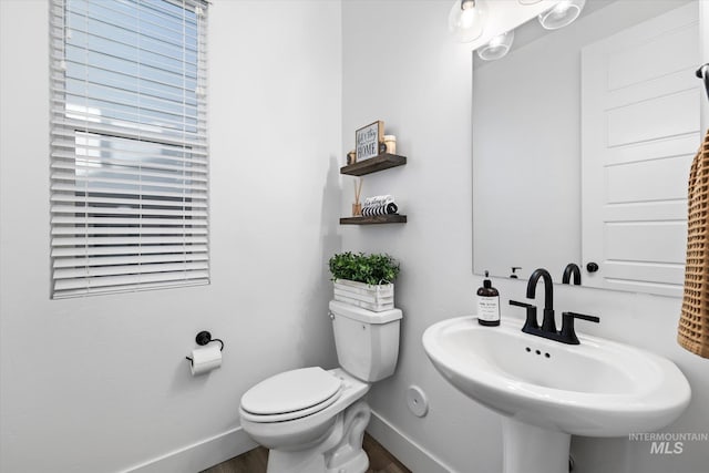 bathroom featuring toilet, wood finished floors, baseboards, and a sink