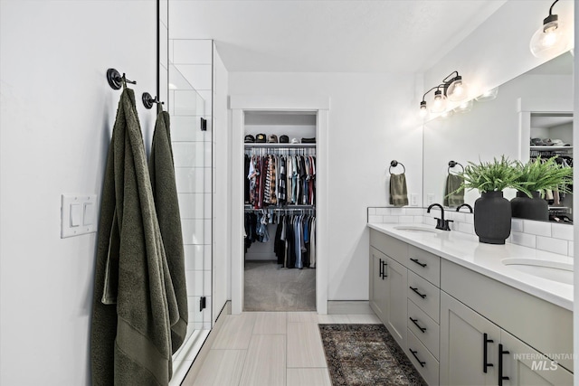 bathroom with double vanity, a stall shower, a walk in closet, and a sink