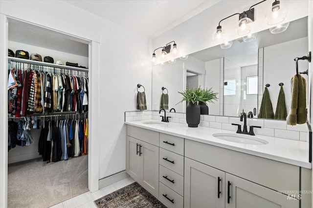 bathroom with double vanity, a walk in closet, and a sink