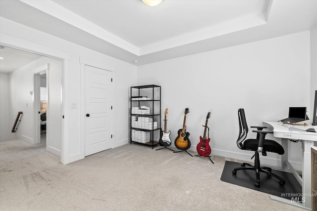 carpeted office space featuring baseboards and a tray ceiling