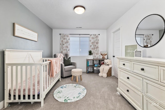 carpeted bedroom with a nursery area and visible vents