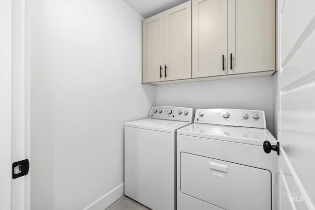 laundry area with baseboards, cabinet space, and separate washer and dryer