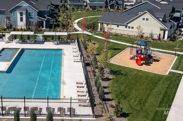 view of swimming pool with playground community, a residential view, a lawn, and fence