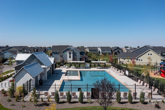 community pool with a patio area, fence, and a residential view